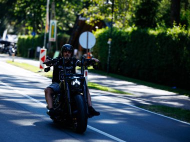 Faaker See, Avusturya - 01 Eylül 2025: Erkek motosikletçi, Avrupa Bisiklet Haftası boyunca resimli bir yolda Harley Davidson sürüyor.