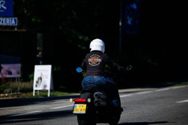 Faaker See, Avusturya - 01 Eylül 2025: Harley-Davidson ceketli bisikletçi Avrupa Bisiklet Haftası boyunca motosiklet sürüyor, özgürlük ve maceranın özünü yakalıyor