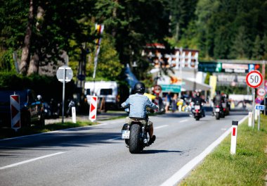 Faaker See, Avusturya - 01 Eylül 2025: Motosiklet meraklısı Avrupa Bisiklet Haftası sırasında diğer motosikletçiler ve hareketli manzaralarla birlikte pitoresk yolda geziyor