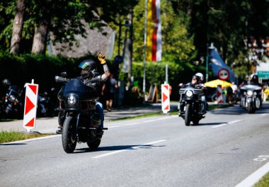 Faaker See, Avusturya - 01 Eylül 2025: Motosikletçi, güneşli bir günde Harley-Treffen 'in canlı atmosferinin tadını çıkararak Avrupa Bisiklet Haftası' nda diğer motosikletçileri karşıladı