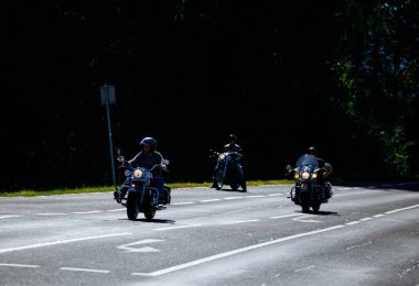 Faaker See, Avusturya - 01 Eylül 2025: Harley-Davidson motosikletli üç motorcu Avrupa Bisiklet Haftası boyunca güneşli bir yolda seyrederek özgürlük ve maceranın özünü yakalıyorlar