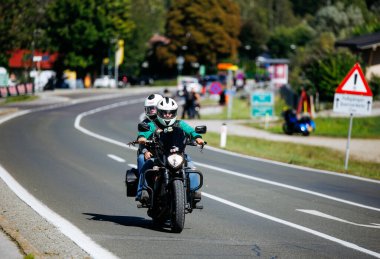 Faaker See, Avusturya - 01 Eylül 2025: Kasklı motosiklet meraklıları dolambaçlı bir yolda Avrupa Bisiklet Haftası ve Harley-Treffen 'in heyecanını yakalıyorlar