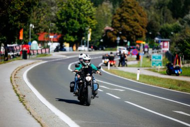 Faaker See, Avusturya - 01 Eylül 2025: Avrupa Bisiklet Haftası boyunca motosiklet sürücüleri, yemyeşil ve motosiklet arkadaşlarıyla çevrili, manzaralı bir yolda seyahat ediyorlar