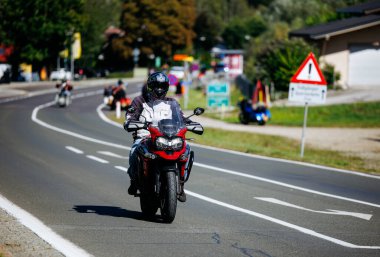 Faaker See, Avusturya - 01 Eylül 2025: Avrupa Bisiklet Haftası 'nda motorsiklet meraklısı, çevresi zengin manzaralı ve motorcu arkadaşlarıyla çevrili virajlı yolda gidiyor