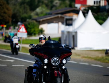 Faaker See, Avusturya - 01 Eylül 2025: Çizgili miğferli erkek motosikletçi, Avrupa Bisiklet Haftası 'nda siyah Harley Davidson motosikleti sürüyor.