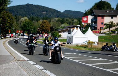 Faaker See, Avusturya - 01 Eylül 2025: Motosikletçiler Avrupa Bisiklet Haftası boyunca Harley-Davidson bisikletleri ve canlı festival atmosferinin yer aldığı manzaranın keyfini çıkarıyorlar