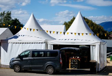 Faaker, Avusturya - 01 Eylül 2025: Avrupa Bisiklet Haftası 'nda siyah minibüs beyaz çadırların yanına kurulmuş, renkli bayraklarla canlı bir ortam yaratıyor