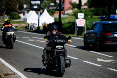 Faaker See, Avusturya - 01 Eylül 2025: Gri sakallı bisikletçi Harley motosikleti sürüyor Avrupa Bisiklet Haftası boyunca manzaralı yolda, motosiklet kültürünün özünü yakalıyor
