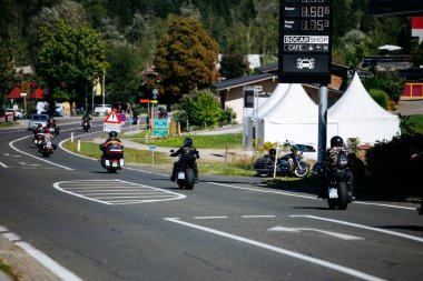 Faaker See, Avusturya - 01 Eylül 2025: Avrupa Bisiklet Haftası 'nda motosikletçiler, yemyeşil bir yol üzerinde Harley-Davidson motosikletlerinin yer aldığı gezinin keyfini çıkarıyorlar.