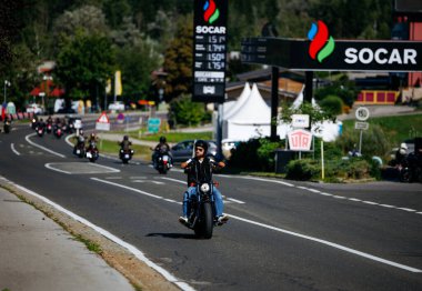 Faaker See, Avusturya - 01 Eylül 2025: Harley-Davidson motosiklet sürücüsü, Avrupa Bisiklet Haftası 'nda motosikletli arkadaşlarıyla birlikte turistik manzaranın tadını çıkarıyor