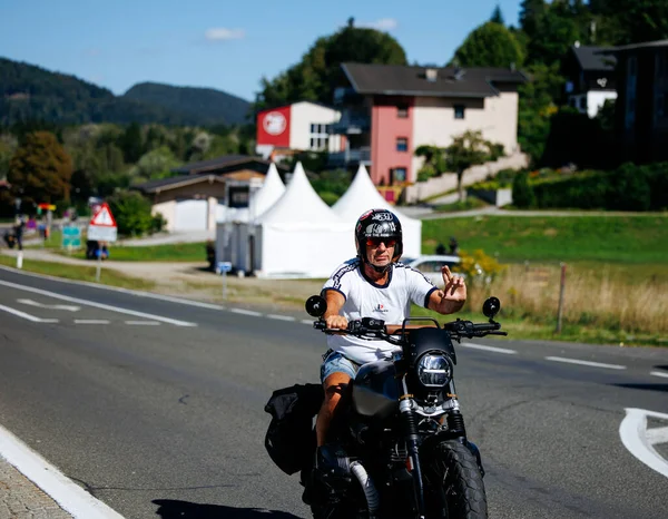 Faaker See, Avusturya - 01 Eylül 2025: Avrupa Bisiklet Haftası boyunca siyah motosiklet sürerken erkek motorcu dalgaları etkinliğin ruhunu yansıtıyor