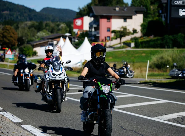 Faaker See, Avusturya - 01 Eylül 2025: Motosikletliler Avrupa Bisiklet Haftası 'na katılarak, yemyeşil yollarla çevrili manzaralı bir yolda el sallıyorlar