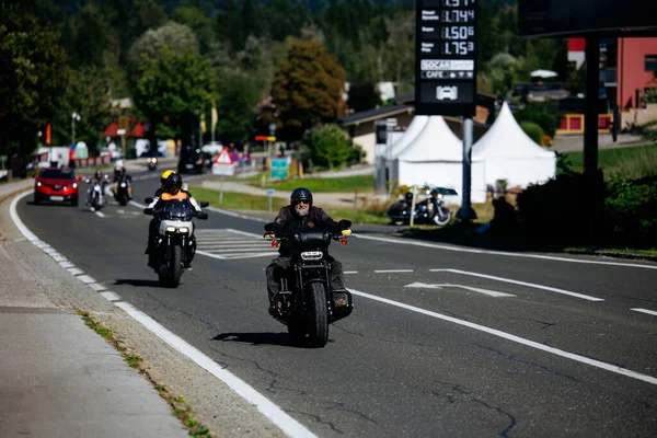 Faaker See, Avusturya - 01 Eylül 2025: Harley-Davidson bisikletleri ve canlı festival atmosferinin yer aldığı Avrupa Bisiklet Haftası boyunca manzaralı yolda motosikletçiler