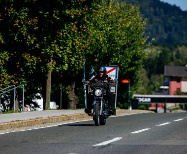 Faaker See, Avusturya - 01 Eylül 2025: Harley-Davidson motosikletli motosiklet Avrupa Bisiklet Haftası 'nda manzaralı yolda seyrediyor.