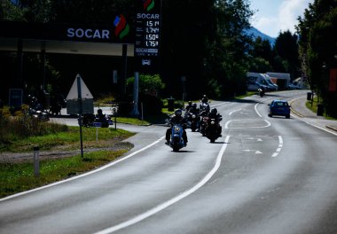 Faaker See, Avusturya - 01 Eylül 2025: Motosikletçiler Avrupa Bisiklet Haftası boyunca Harley-Davidson bisikletleri ve SOCAR istasyonuyla güzel bir yolda gezinti yapıyorlar.