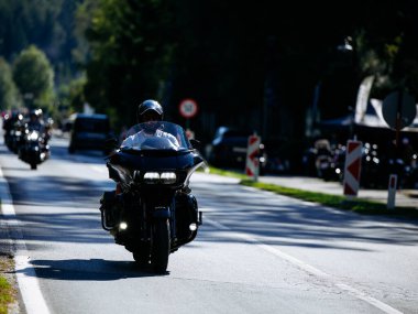Faaker See, Avusturya - 01 Eylül 2025: Harley-Davidson motosiklet sürücüsü Avrupa Bisiklet Haftası sırasında yanında diğer motosikletçilerle birlikte pitoresk yolda seyahat ediyor