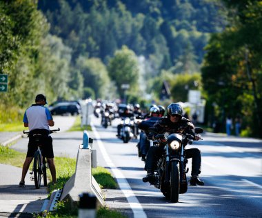 Faaker See, Avusturya - 01 Eylül 2025: Motosikletçiler Avrupa Bisiklet Haftası boyunca Harley-Davidson motosikletleri ve yemyeşil otlakların yer aldığı manzaralı bir yolda gezinti yapıyorlar