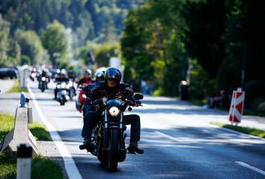 Faaker See, Avusturya - 01 Eylül 2025: Harley-Davidson motosikletleri Avrupa Bisiklet Haftası 'nın özünü ve bisiklet yarışının heyecanını yansıtan pitoresk bir yolda ilerliyor.