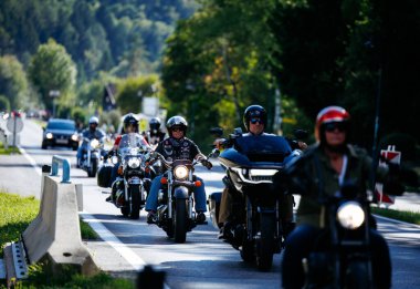 Faaker See, Avusturya - 01 Eylül 2025: Motosikletçiler Avrupa Bisiklet Haftası sırasında Harley-Davidson motosikletleri ve renkli ağaçların yer aldığı pitoresk bir yolda gezinti yapıyorlar