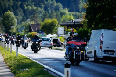 Faaker See, Avusturya - 01 Eylül 2025: Motosikletçiler Avrupa Bisiklet Haftası boyunca Harley-Davidson bisikletleri ve canlı çevrenin yer aldığı manzaralı bir yolda gezintiye çıktılar