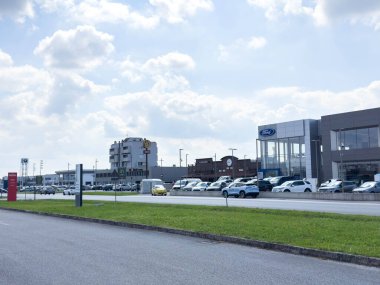 Udine, İtalya - 26 Ağustos 2025: Ford bayiliğinde arka planda bir otel ve dükkanlar görülebilen açık gökyüzü altında birden fazla araba sergileniyor