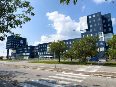 Udine, İtalya - 26 Ağustos 2025: Çağdaş bina, yeşil ve mavi gökyüzü ile çevrili büyük cam pencereler ve eşsiz tasarımlar içeriyor.