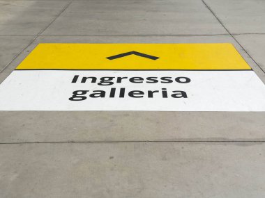 Udine, İtalya - 26 Ağustos 2025: Asfalt işareti, ziyaretçileri keşif yapmaya davet eden sarı ok ve koyu siyah metinle galeri girişine açık bir yön gösteriyor