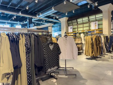 Udine, İtalya - 26 Ağustos 2025: Giysi mağazası raflarda polka noktalı gömlekler ve nötr renkler de dahil olmak üzere çeşitli giysiler sergiliyor, müşterileri alışverişe davet ediyor