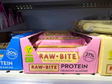 Udine, İtalya - 26 Ağustos 2025: Çıtır badem aromalı çiğ ısırık protein barları, organik ve vejetaryen seçenekleri vurgulayarak bir süpermarket rafında düzgünce düzenlenmiştir