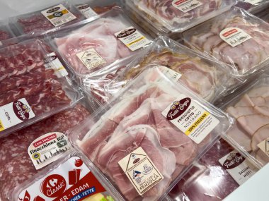 Udine, İtalya - 26 Ağustos 2025: Prosciutto, salam ve jambon içeren paketlenmiş meze etleri, tazelik ve seçilimin ön plana çıkarıldığı bir bakkalda düzgünce düzenleniyor