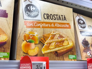 Udine, İtalya - 26 Ağustos 2025: Crostata tatlı kutusu kayısı reçelli bir dilim sunuyor, kırsal ahşap bir zemin üzerine kurulmuş, ürünün görsel çekiciliğini artırıyor