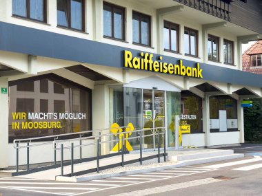 Moosburg, Avusturya - 27 Ağustos 2025: Moosburg 'daki Raiffeisenbank cephesinde müşteriler için parlak tabelalı ve erişilebilirlik rampalı çağdaş tasarım yer alıyor