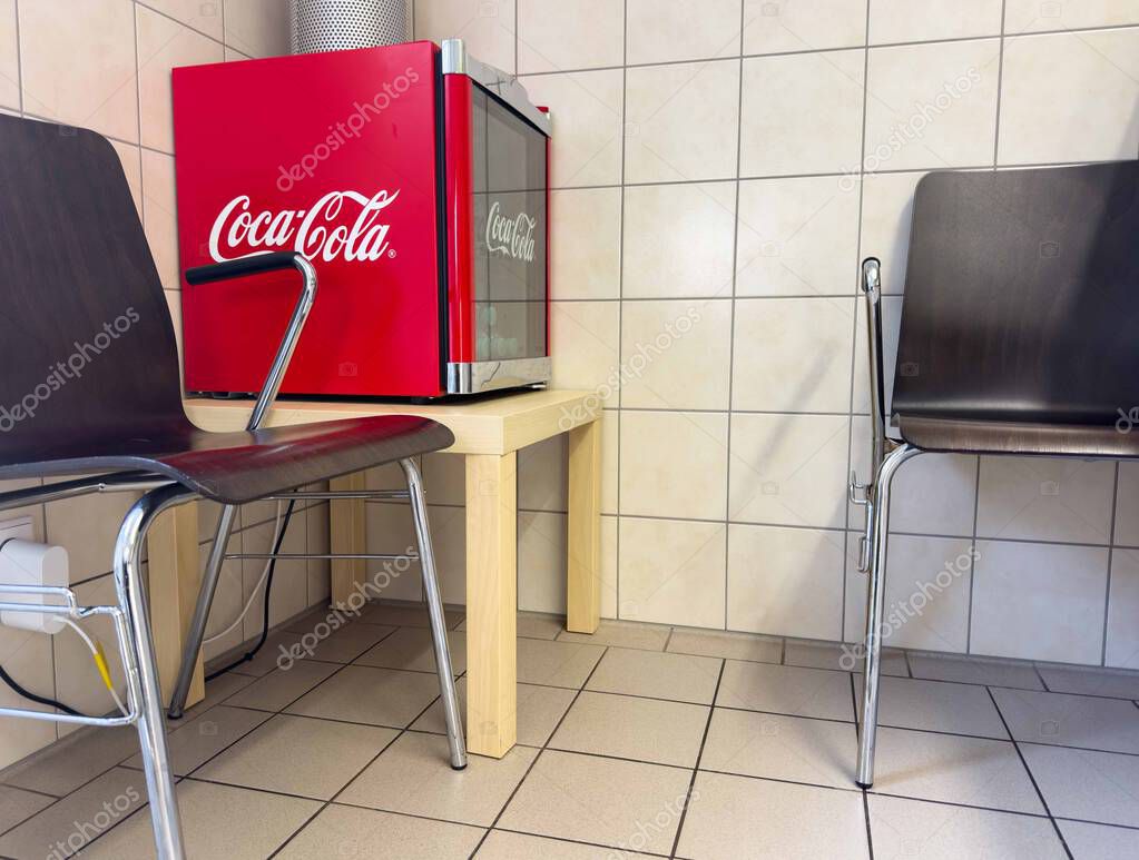 Moosburg, Austria - August 27, 2025: Coca-Cola vending machine is positioned in a welcoming waiting area with stylish chairs and tiled flooring