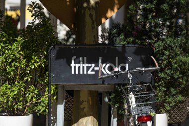 Villach, Avusturya - Eylül 04, 2025: Fritz-Kola tabelası şehir atmosferini geliştiren yeşillik ve bisikletiyle canlı bir açık alanda sergilenmektedir.