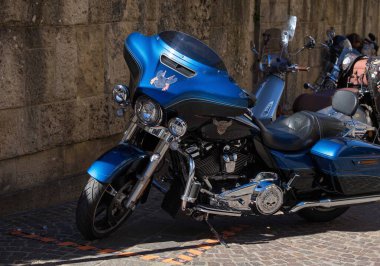 Villach, Avusturya - Eylül 04, 2025: Mavi motosiklet taştan bir duvarın karşısında duruyor, krom özelliklerini ve bisiklet meraklıları için modern tasarımı vurguluyor