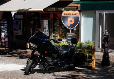 Villach, Avusturya - Eylül 04, 2025: Siyah motosiklet 'Sadece Motorcular' tabelası olan bir dükkanın önüne park edilmiş, enerjik bir şehir havası yaratıyor.
