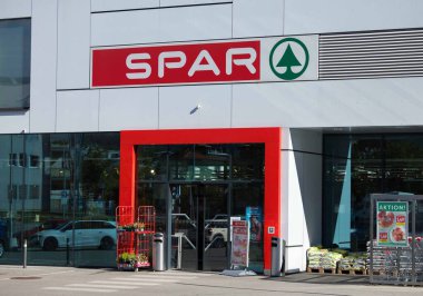 Villach, Avusturya - Eylül 04, 2025: SPAR süpermarketi kırmızı aksanlı ve cam kapılı çağdaş bir girişe sahip, müşterileri canlı bir perakende alanına kabul eden