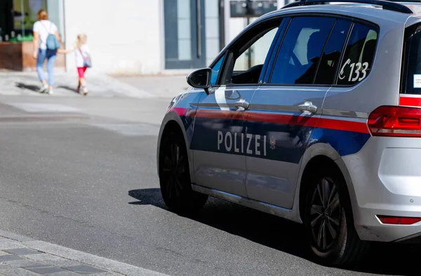 Villach, Avusturya - Eylül 04, 2025: Polis aracı yayalarla birlikte şehir caddesinde konuşlandı, halkın güvenliğini ve günlük yaşamını ön plana çıkardı