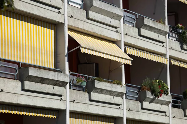 Villach, Avusturya - Eylül 04, 2025: Sarı çizgili tenteleri ve renkli çiçek kutularıyla şehir mimarisi ve tasarımı ön plana çıkaran apartman binası