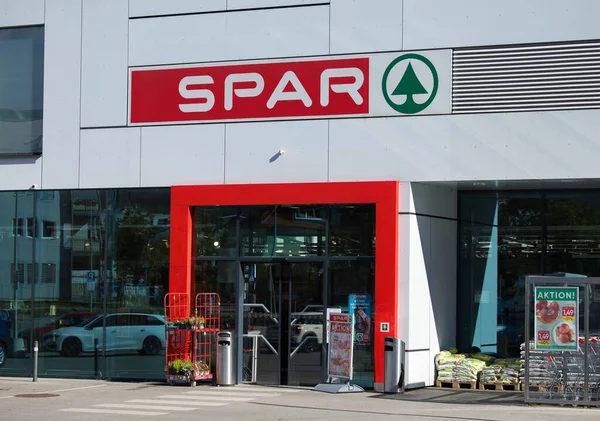 Villach, Avusturya - Eylül 04, 2025: SPAR süpermarketi kırmızı aksanlı ve cam kapılı çağdaş bir girişe sahip, müşterileri canlı bir perakende alanına kabul eden