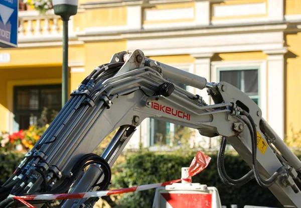Villach, Avusturya - Eylül 04, 2025: Takeuchi kazıcı kolu kentsel inşaat sahasında renkli binalarla birlikte hidrolik hortumlar içeriyor