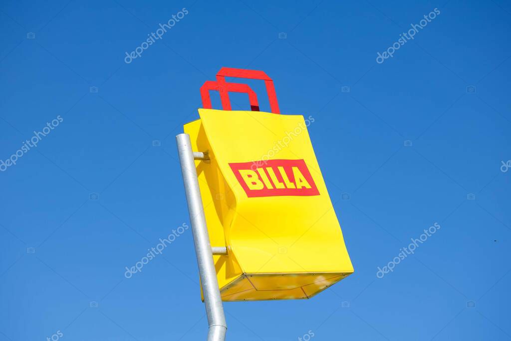 Villach, Austria - September 04, 2025: BILLA brand sign prominently displayed in yellow against a clear blue sky, emphasizing brand visibility and color contrast
