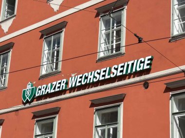 Graz, Avusturya - Eylül 06, 2025: Grazer Wechselseitige tabelası turuncu bir binada belirgin bir şekilde sergilenmiş, kentsel tasarım ve parlak renkleri kopya alanı ile vurguluyor