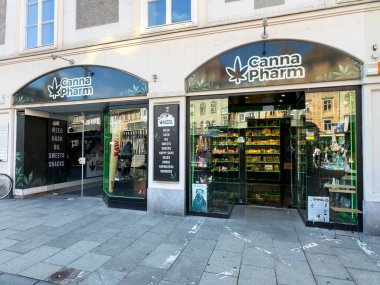 Graz, Avusturya - Eylül 06, 2025: Canna Pharm mağazası renkli vitrinlerle müşterileri çeken canlı bir şehir ortamında esrar ürünleri ve aksesuarları barındırıyor