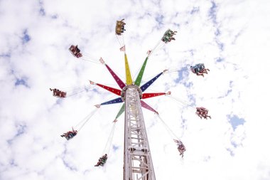 Villach, Avusturya - 30 Temmuz 2025: Villacher Kirchtag Festivali 'nde renkli bir salıncak, bulutlara karşı sürücülerin heyecanını yakalıyor