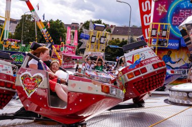 Villach, Avusturya - 30 Temmuz 2025: Çocuklar arka planda renkli gösterilerle Villacher Kirchtag festivalinde harika vakit geçiriyorlar