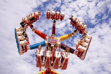 Villach, Avusturya - 30 Temmuz 2025: Villacher Kirchtag festivalinde bulutlu gökyüzüne karşı dönen renkli koltuklar canlı bir atmosfer yaratıyor