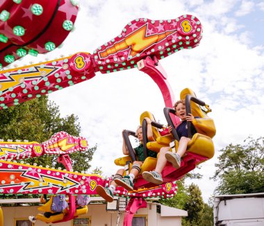 Villach, Avusturya - 30 Temmuz 2025: Çocuklar renkli ışıklar ve şenlikli ortam ile çevrili Villacher Kirchtag 'de heyecanlı bir yolculukta eğleniyorlar