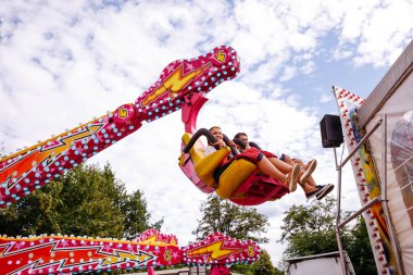 Villach, Avusturya - 30 Temmuz 2025: İki kız Villacher Kirchtag festivalinde heyecan verici bir yolculuk yaşıyor, etrafı renkli dekorasyonlar ve neşe dolu bir ortam ile çevrili.