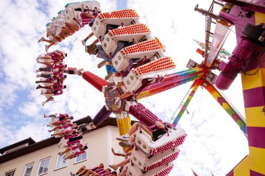 Villach, Avusturya - 30 Temmuz 2025: Villacher Kirchtag festivalinde neşeli binicilerin ve renkli yapıların festival atmosferinde yer aldığı eğlenceli bir gezinti